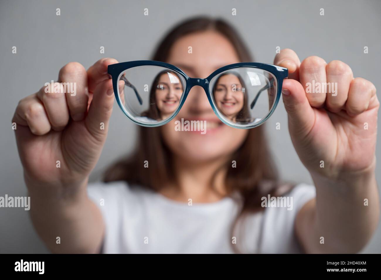 La donna guarda la fotocamera attraverso gli occhiali con un grande sorriso Foto Stock