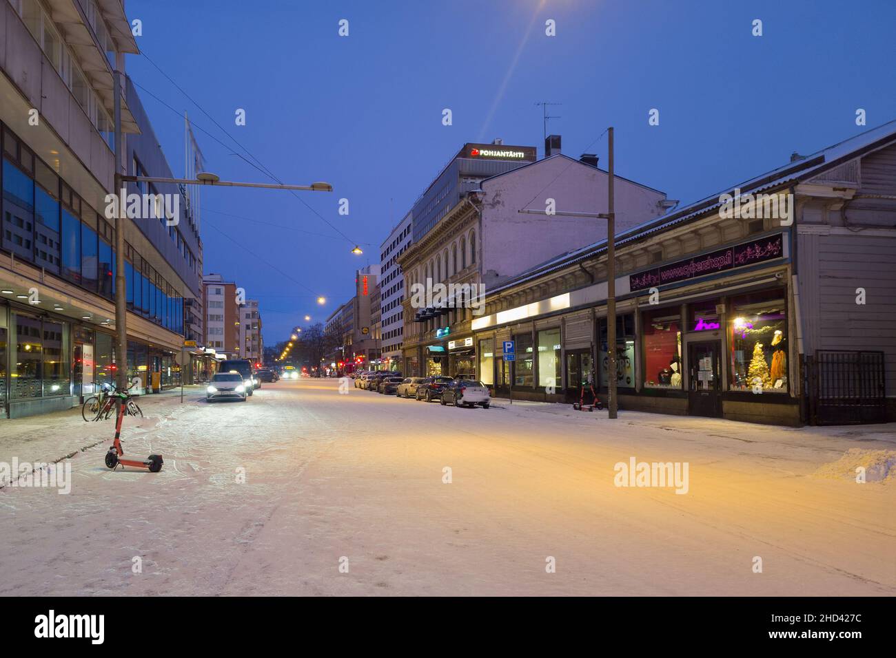 Turku, Finlandia - 24 dicembre 2021: Vista orizzontale della strada notturna di Eerikinkatu Street con parcheggio scooter e Taxi Stop in Forground, Pohjantahti Ins Foto Stock