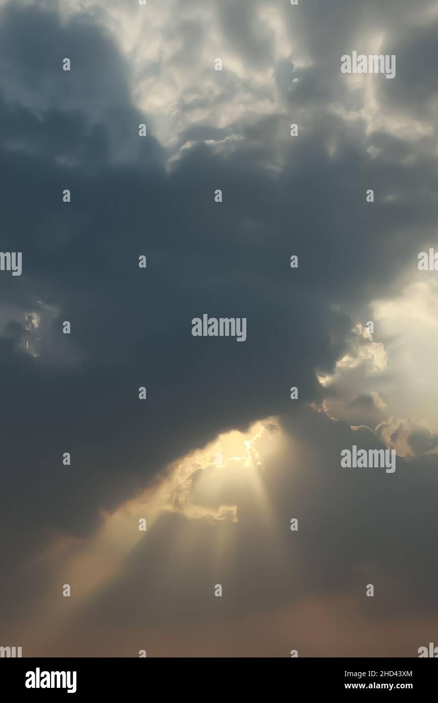 La luce del sole che si irradi attraverso le nuvole tempeste grigie con raggi solari che si illuminano. Foto Stock