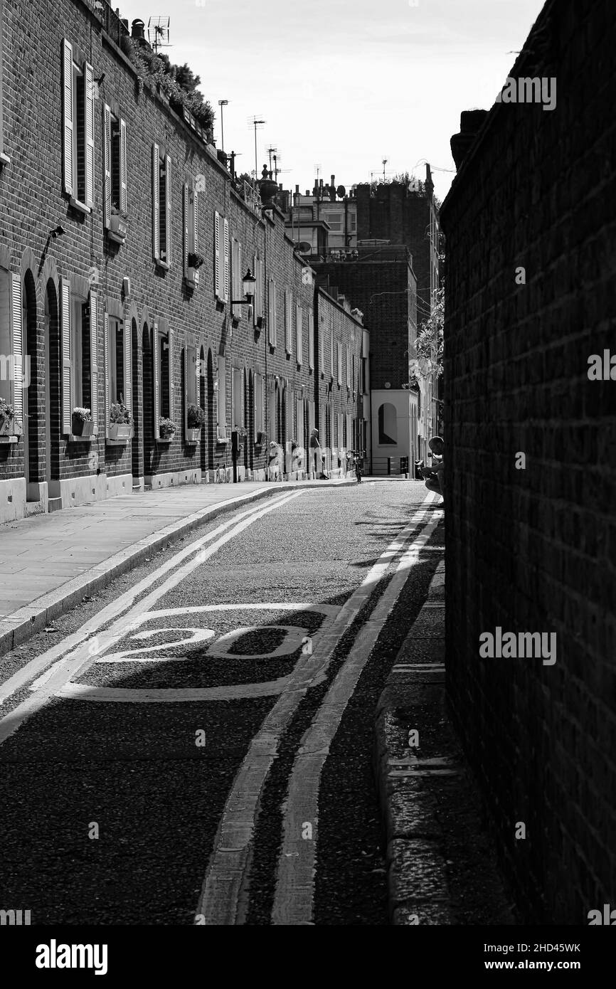 Foto verticale di una strada stretta circondata da edifici, immagine in scala di grigi, Londra Foto Stock