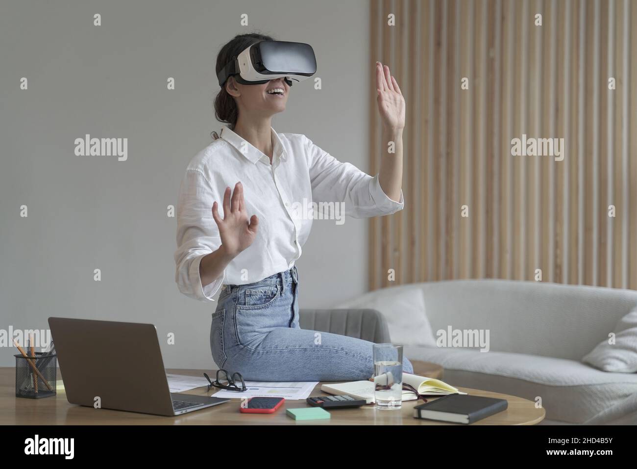 Donna d'affari in abiti eleganti e formali seduti in ufficio e utilizzando le tecnologie di realtà virtuale sul posto di lavoro Foto Stock