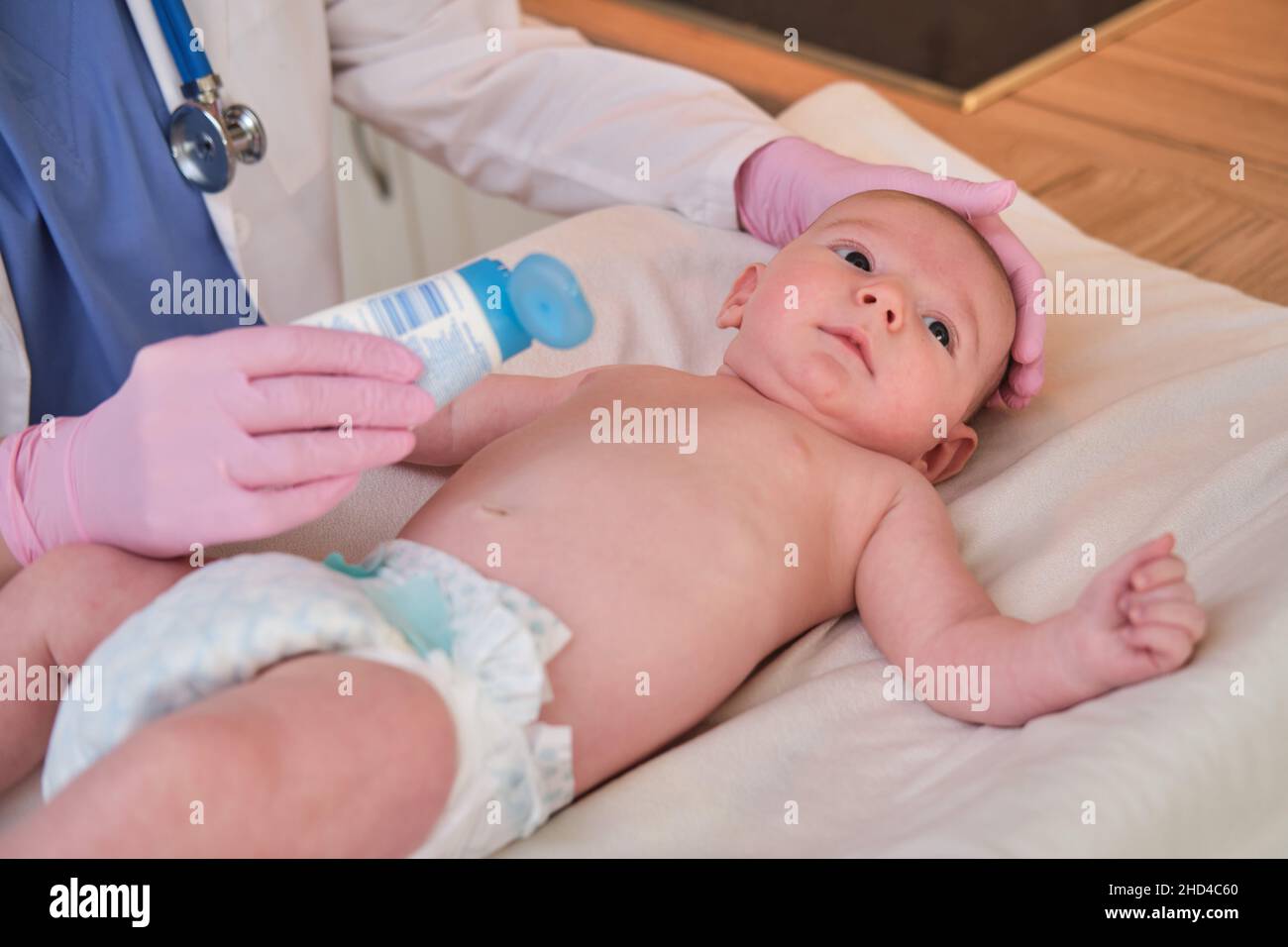 Il medico spalma una crema sulla pelle di un neonato. Infermiere dermatologo in uniforme Foto Stock