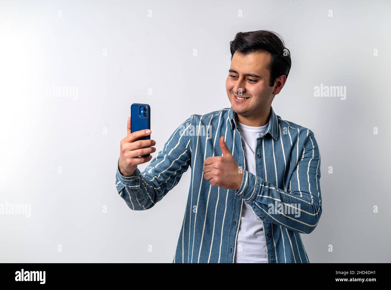 Primo piano di un modello giovane adulto con pelle marrone, videochiamata con smartphone su sfondo bianco isolato. Foto Stock