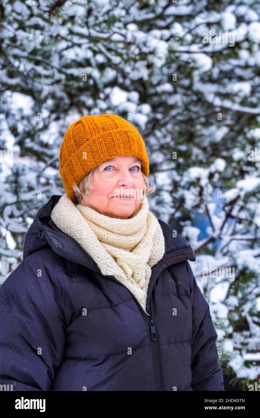 Donna di mezza età all'aperto in inverno con pino innevato Foto Stock