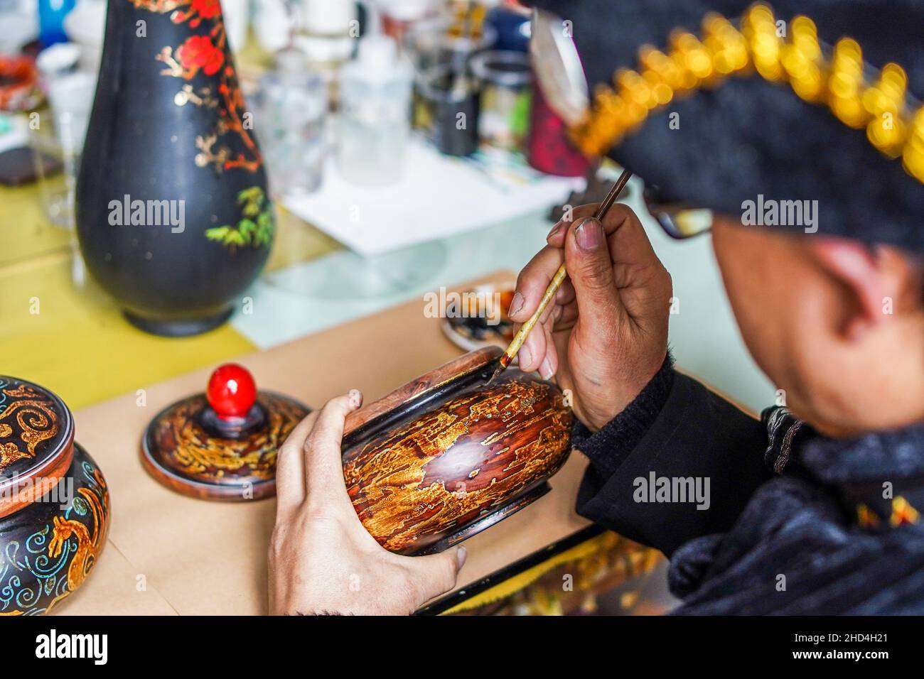 BIJIE, CINA - 3 GENNAIO 2022 - gli operai decorano i prodotti della lacceria alla fabbrica artigianale della lacceria di gaoguang Yifeng nella città di Bijie, G sud-ovest della Cina Foto Stock