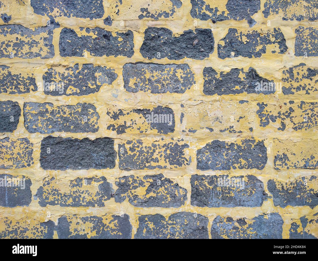 Parete grigia in legno di cinderblock con vernice gialla per peeling Foto Stock