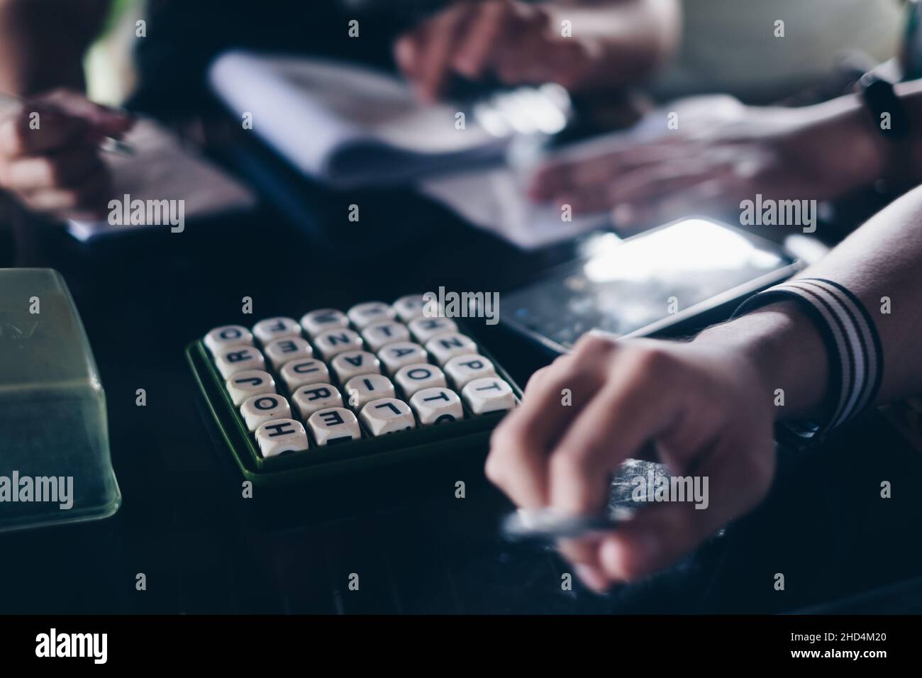 KORONADAL, PH – DEC 25, 2021: Mani di giocatori sul tavolo giocando il popolare gioco di Boggle 5x5. Messa a fuoco selettiva. Foto Stock