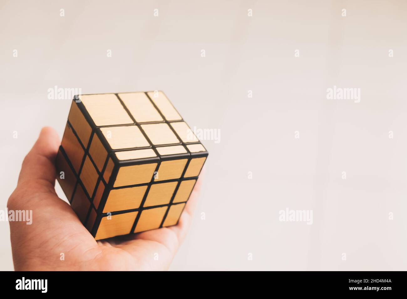 KORONADAL, PH – DEC 26, 2021: Il Cubo di Rubik è stato inventato da Erno Rubik. Mano che tiene un modello oro irregolare completato del puzzle cubo di rubik 3x3. Foto Stock