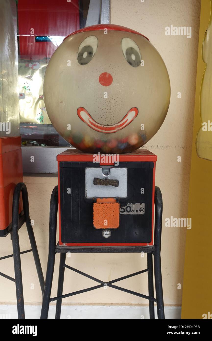 Vecchia macchina di gumball con il viso felice che eroga sfere giocattolo elastiche. Foto Stock
