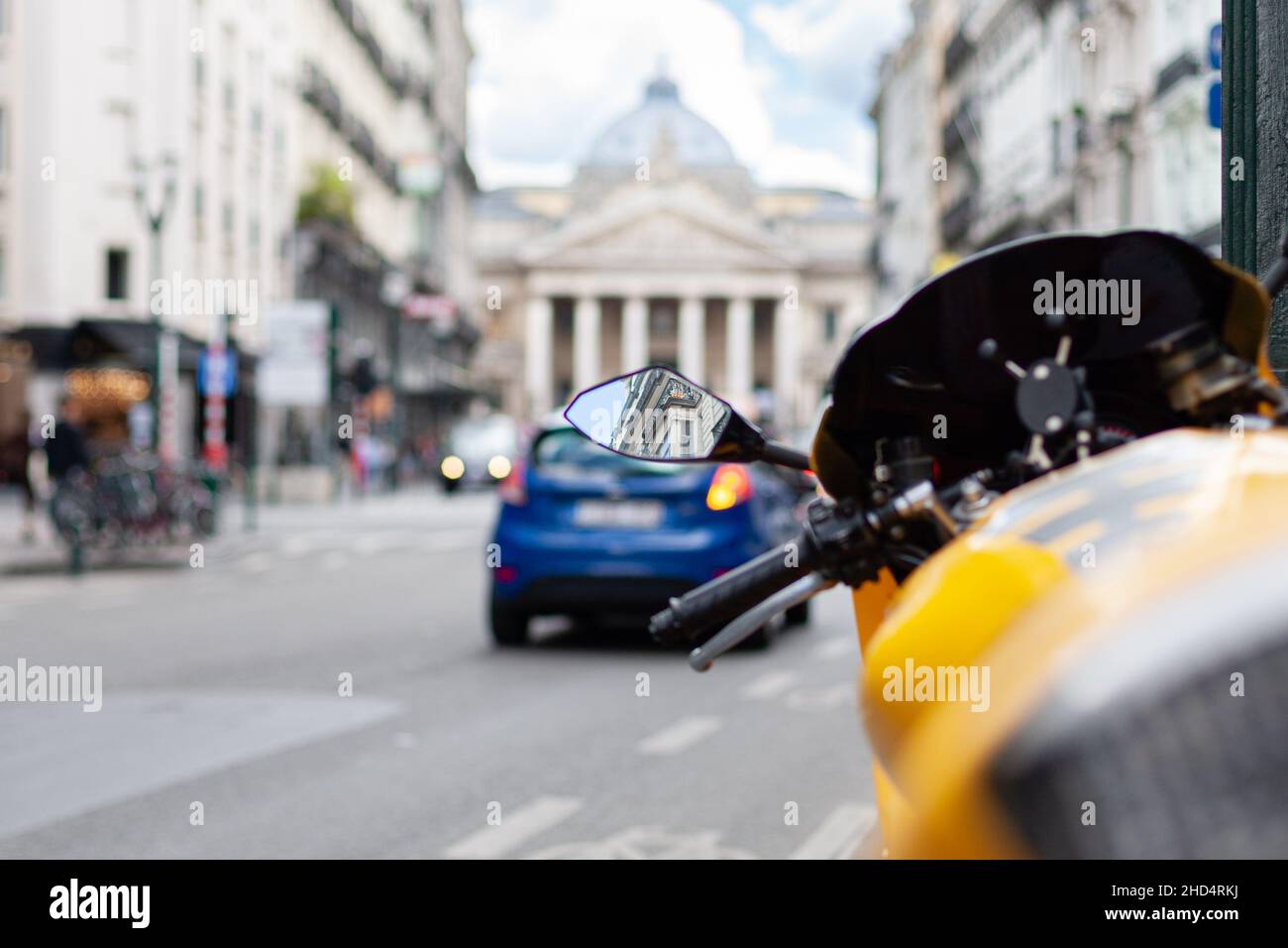 Fuoco selettivo di una bici gialla parcheggiata che riflette un edificio nel suo specchio a Bruxelles, Belgio Foto Stock