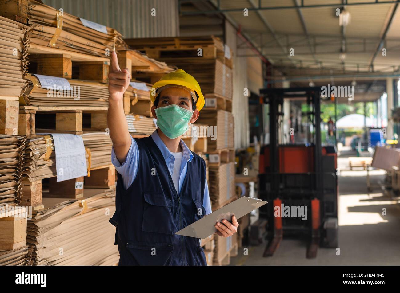 Lavoratore che controlla la materia prima in magazzino per fabbrica industriale, Safety Engineer Foto Stock