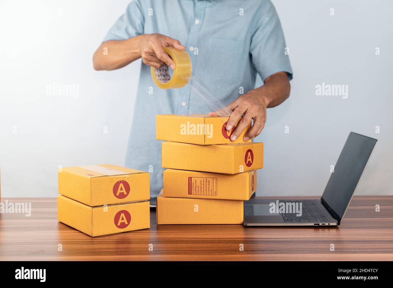 Uomo che usa il nastro per la scatola di imballaggio per vendere il commercio in linea, Foto Stock