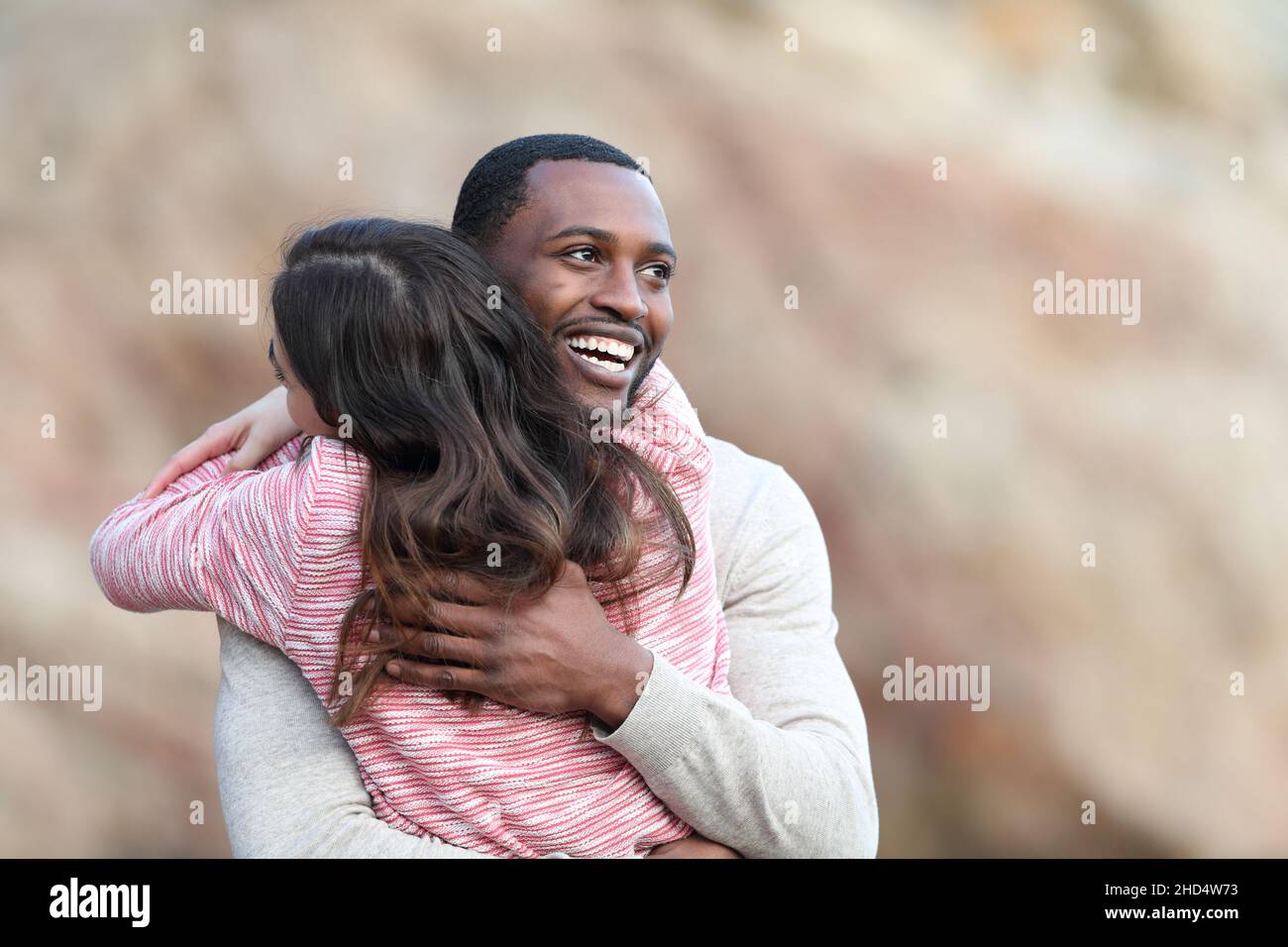 Uomo felice con pelle nera che abbraccia la sua amica caucasica Foto Stock