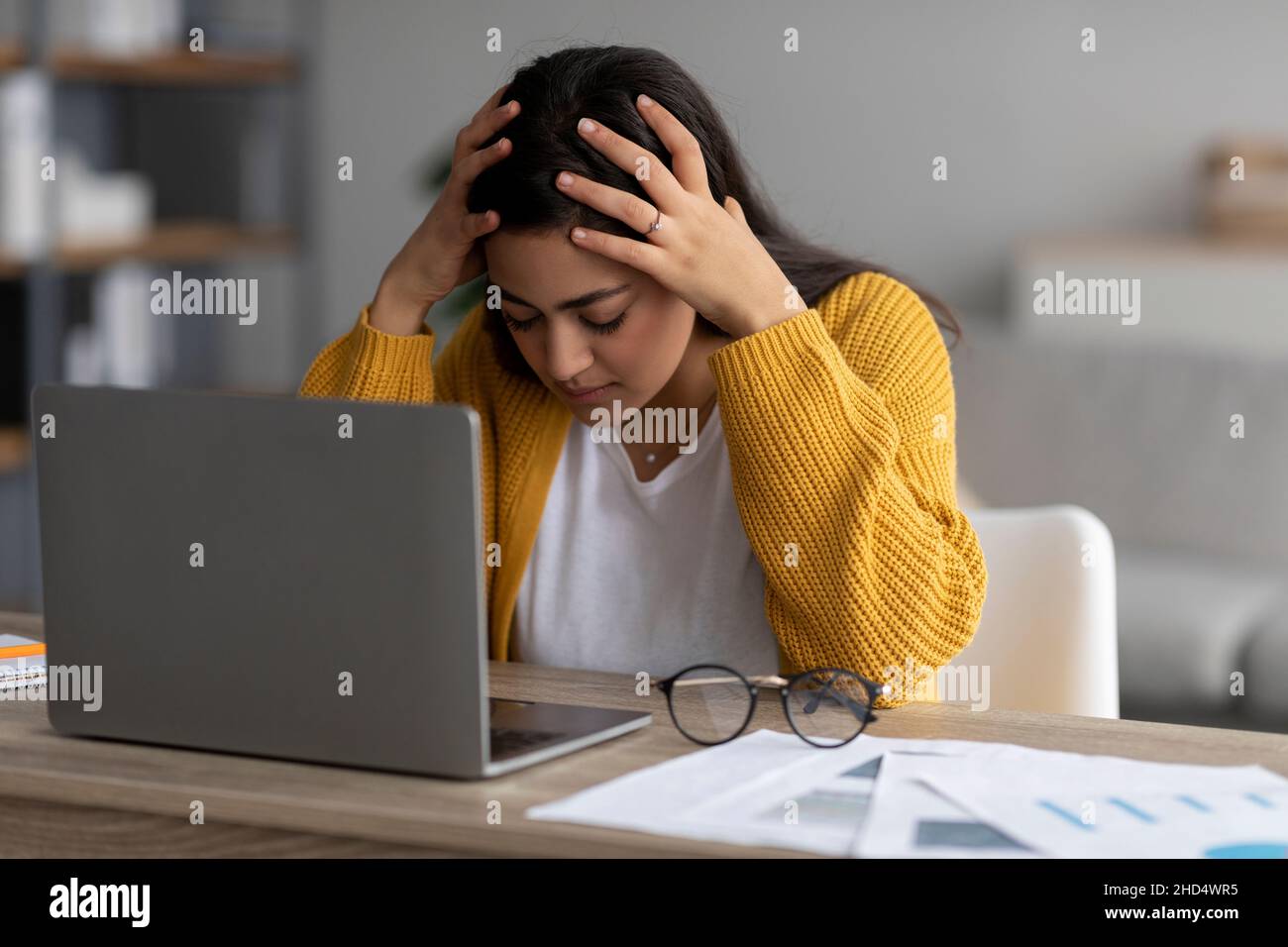 Lavoro stressante, concetto burnout. Ha sottolineato la signora araba che lavora sul laptop e tocca la testa, avendo problemi sul posto di lavoro Foto Stock