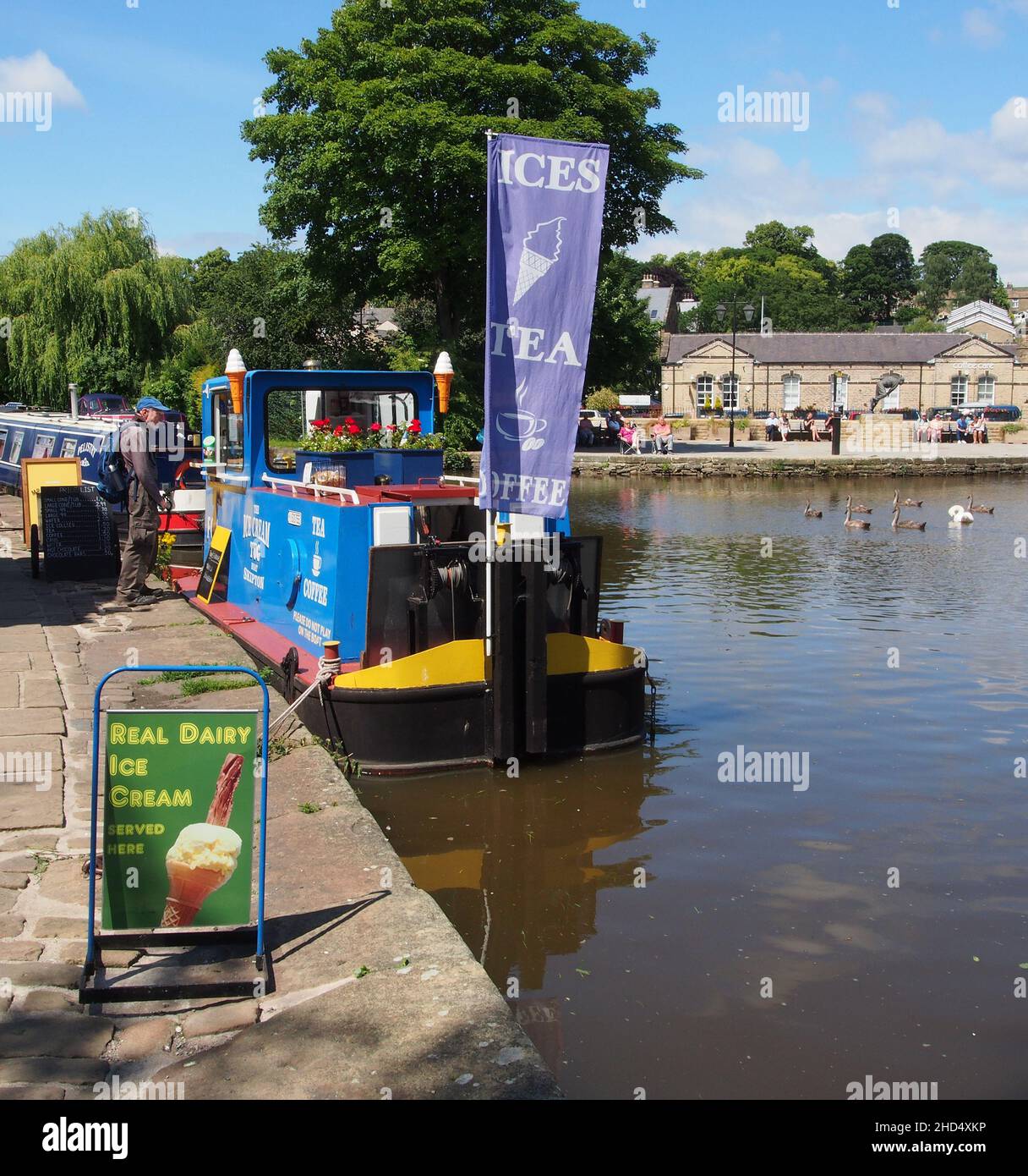 Cliente maschile che acquista rinfreschi dalla barca che vende gelato ormeggiato sul canale Leeds e Liverpool a Skipton, North Yorkshire, Inghilterra. Foto Stock