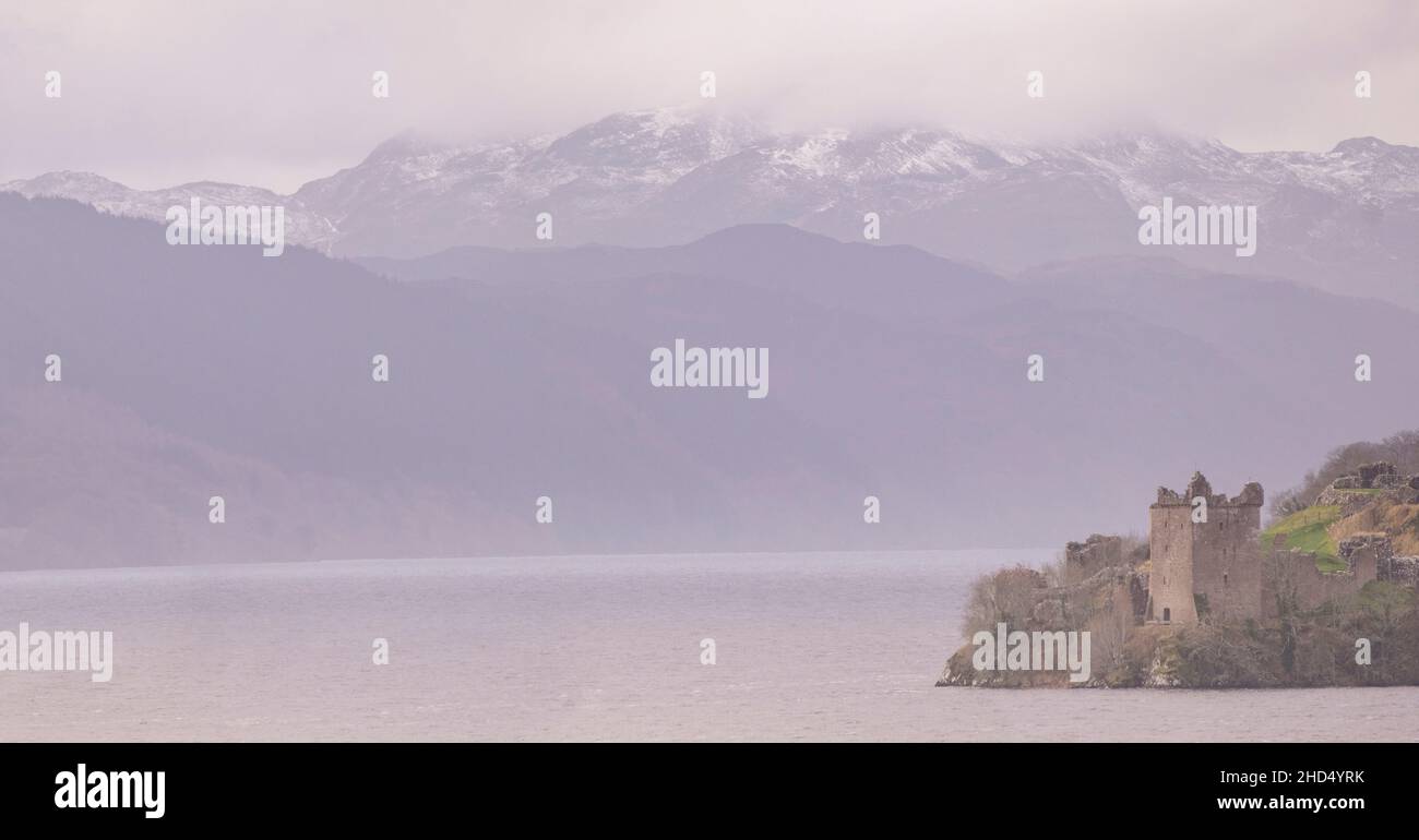 Urquhart Castello in una fredda mattina con la neve in aria e aggrappato alle cime dei Monadhliath Mountains sulla riva meridionale di Loch Ness. Foto Stock