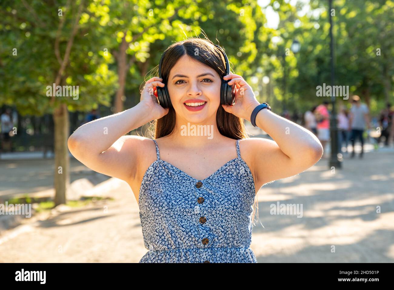 Giovane donna al parco con le cuffie per ascoltare la musica durante la giornata di sole durante la stagione primaverile estiva Foto Stock