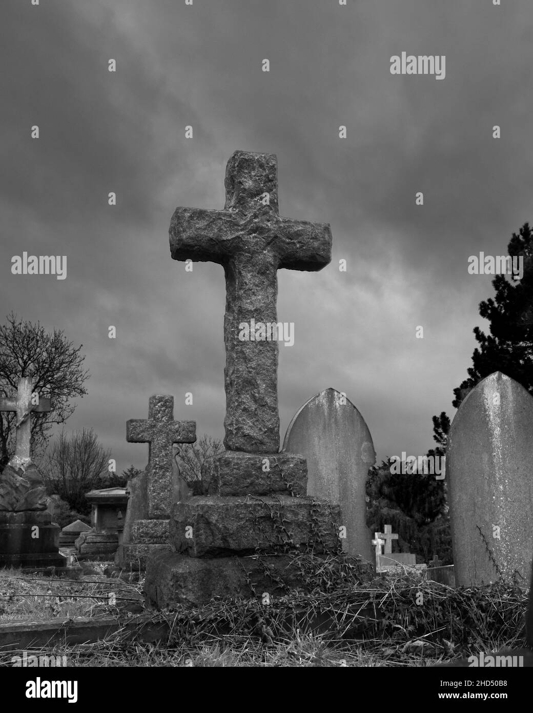 Una pietra ruvida croce si erge orgogliosamente contro un cielo tempestoso - Spital Cemetery, Chesterfield, North East Derbyshire Foto Stock