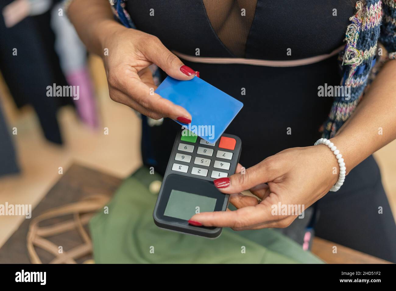 Donna che detiene carta di credito e pagamento elettronico terminale macchina per pagare in negozio di abbigliamento.Cashless e contatto meno concetto Foto Stock