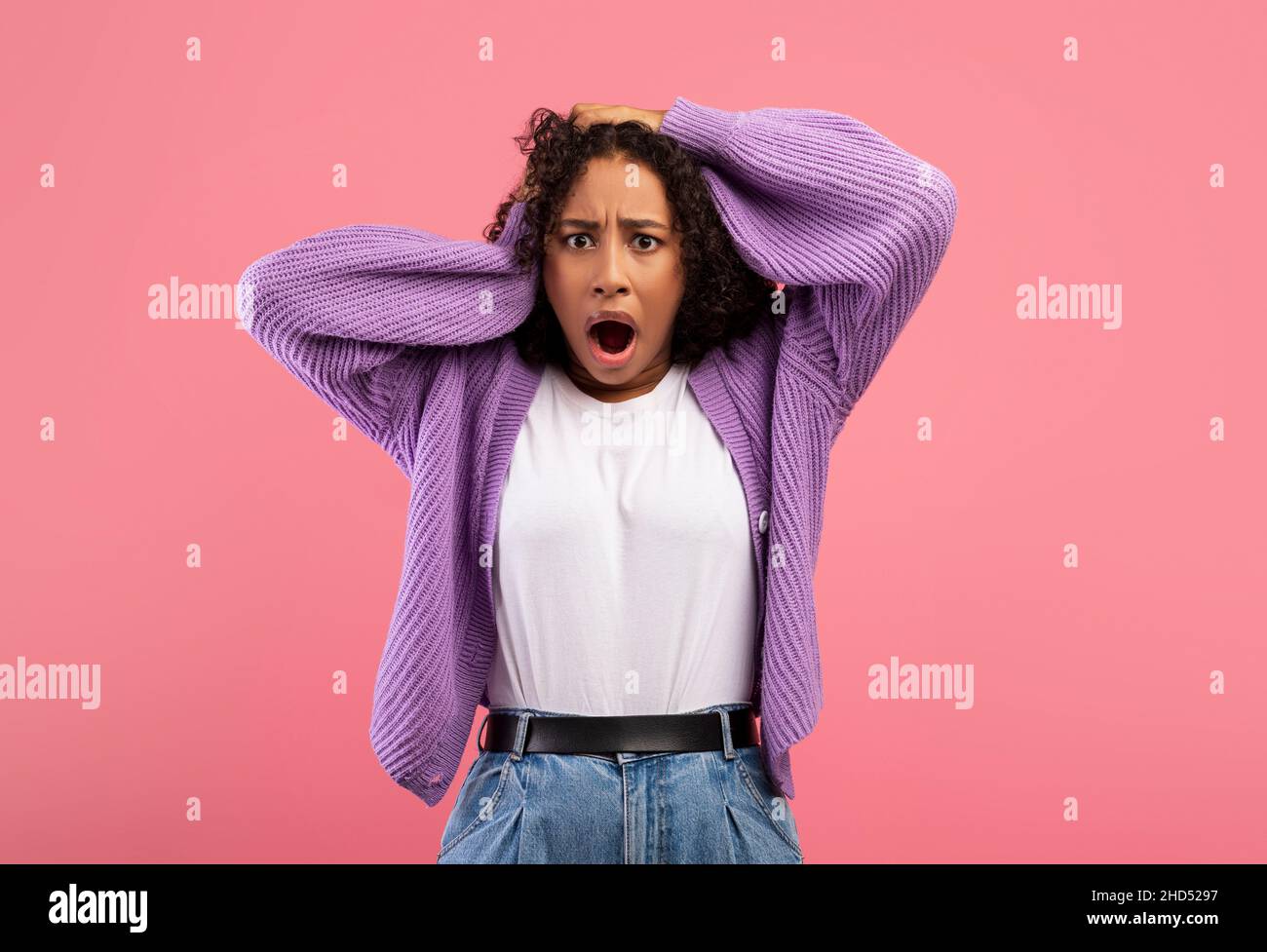 Notizie scioccanti. Donna afroamericana emozionale che tiene la testa in panico su sfondo rosa studio Foto Stock