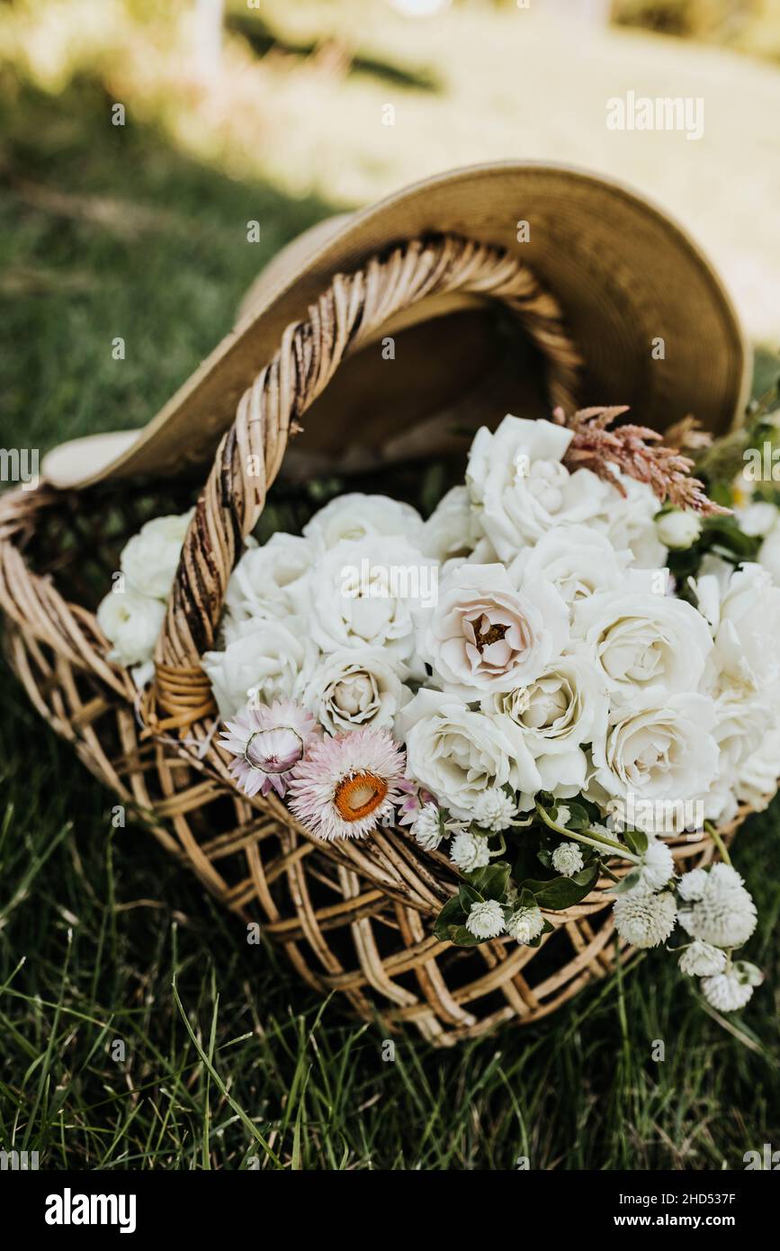 Primo piano di fiori freschi in un cesto tessuto con grande cappello da sole Foto Stock