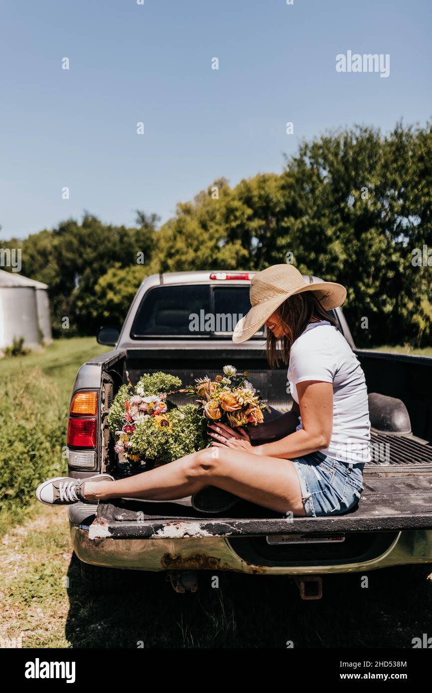 Le donne siedono sul letto del camion mentre organizzano i fiori freschi durante l'estate Foto Stock