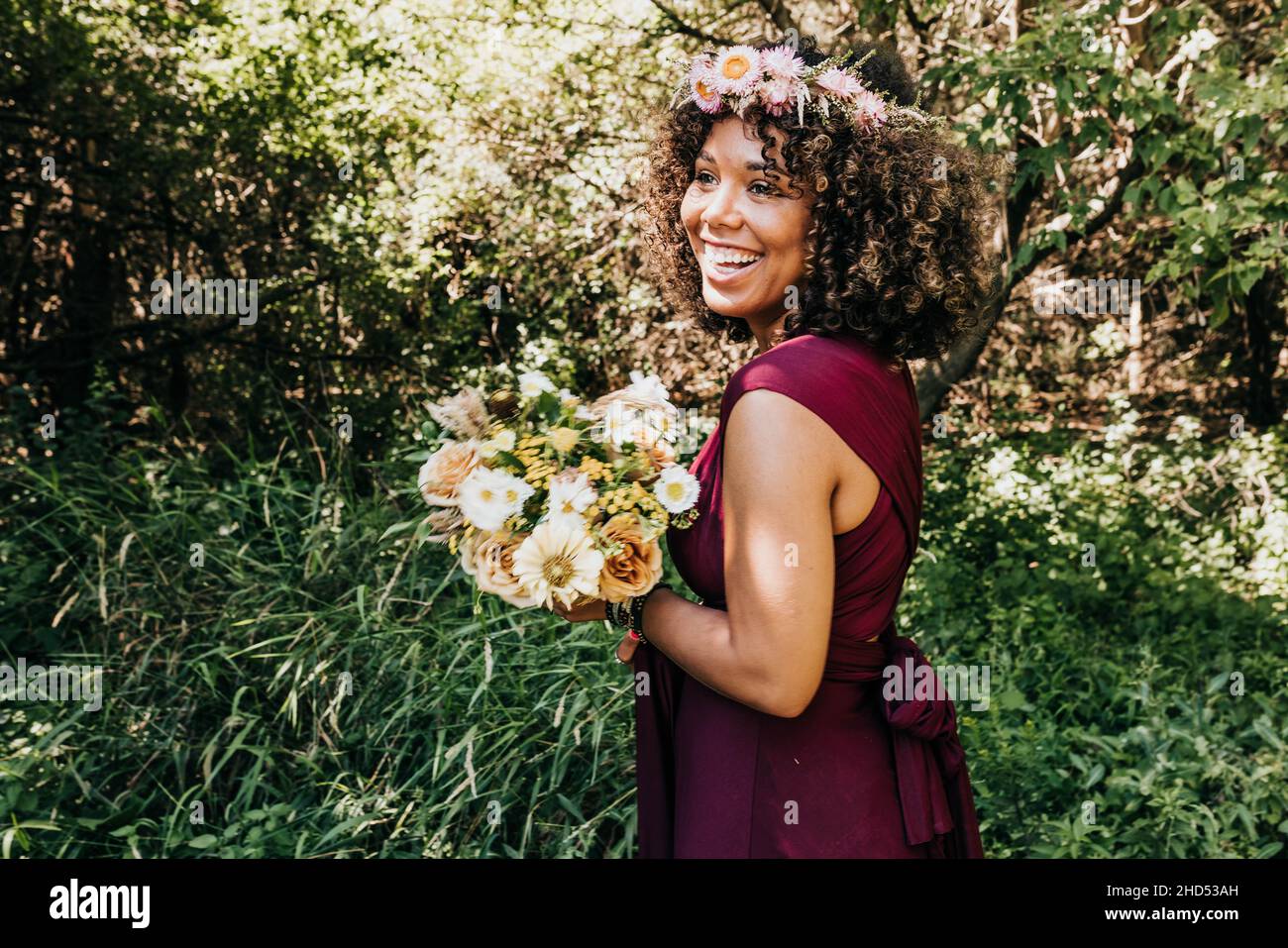 Donna sorridente in abito da sposa e corona di fiori si erge in legno Foto Stock