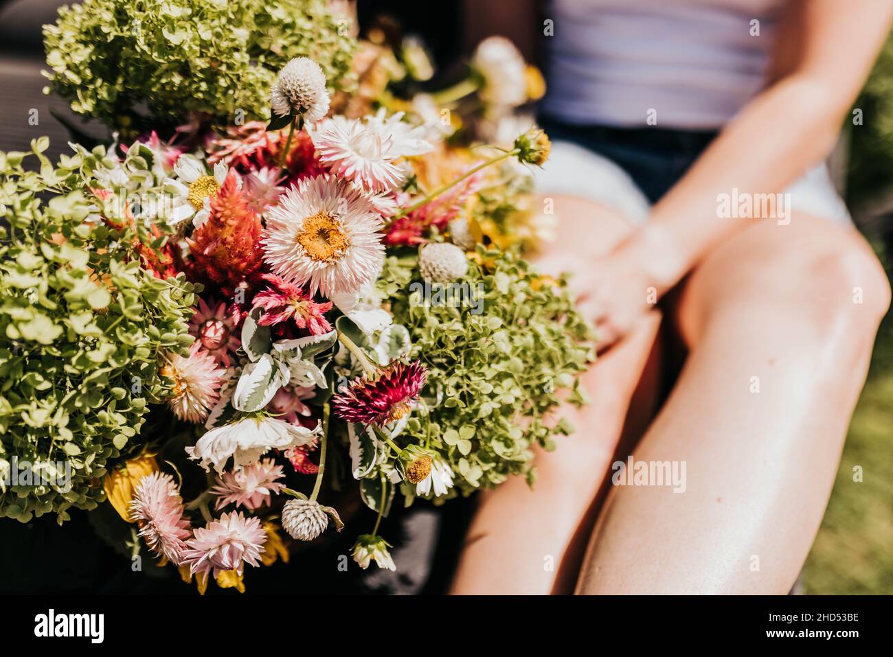 Primo piano di donna seduta accanto ai fiori all'aperto in estate Foto Stock