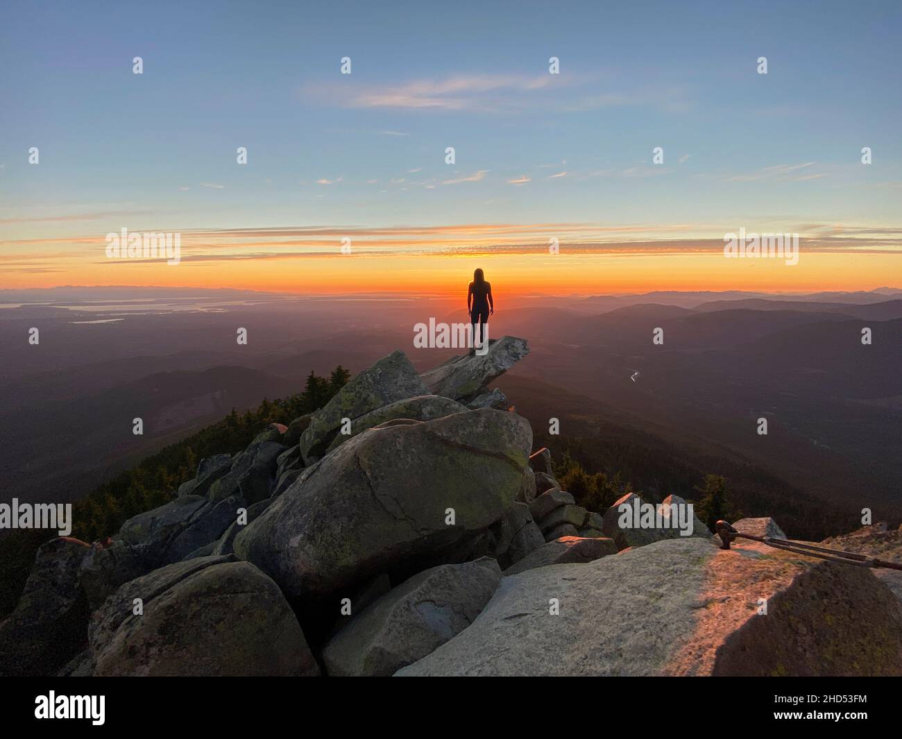 Silhouette di una donna in piedi su una cima di montagna al tramonto Foto Stock