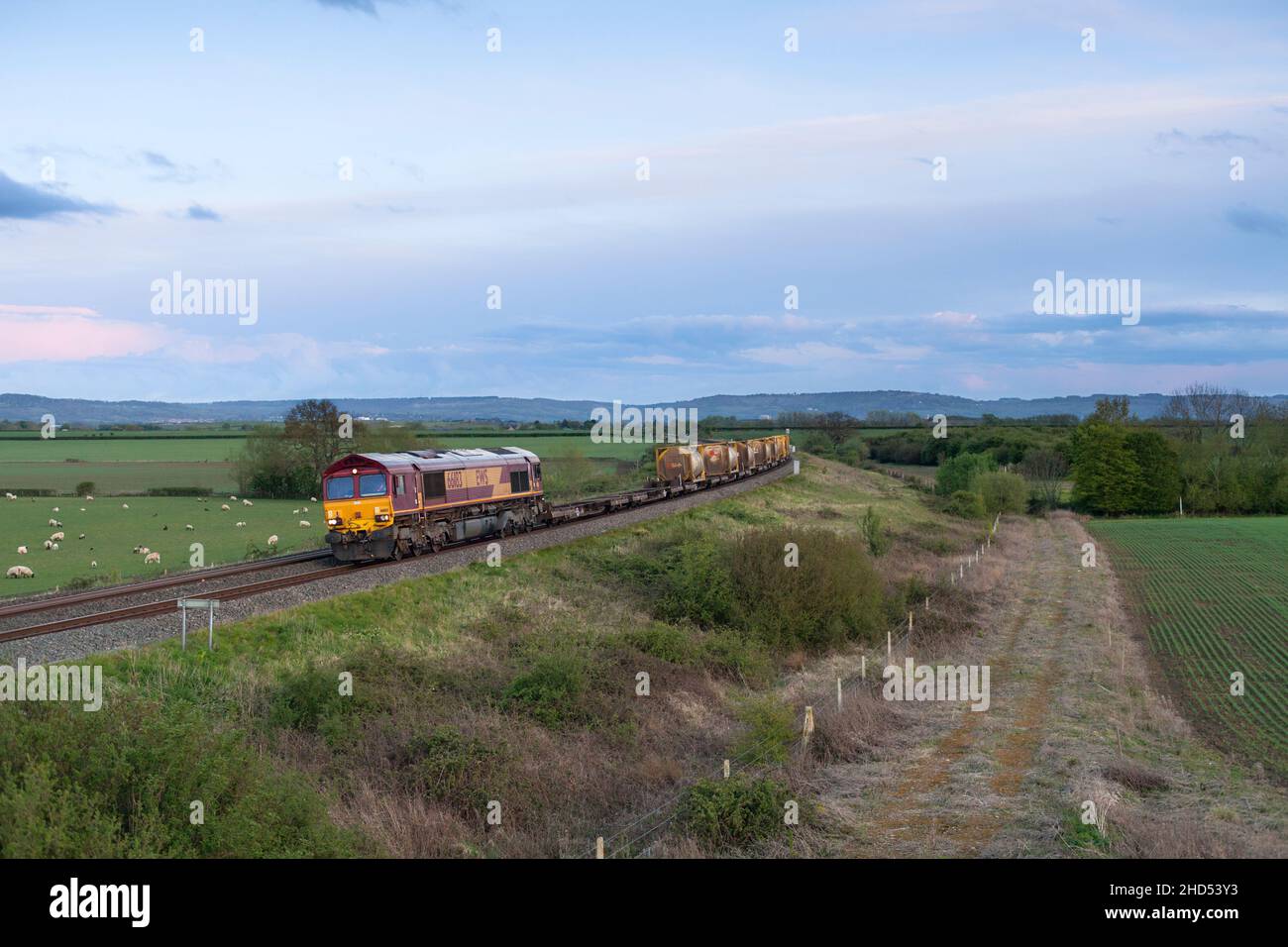 DB Cargo EWS livrea classe 66 Locomotiva diesel che trasporta un treno merci di contenitori cisterna ISO attraverso la campagna Foto Stock