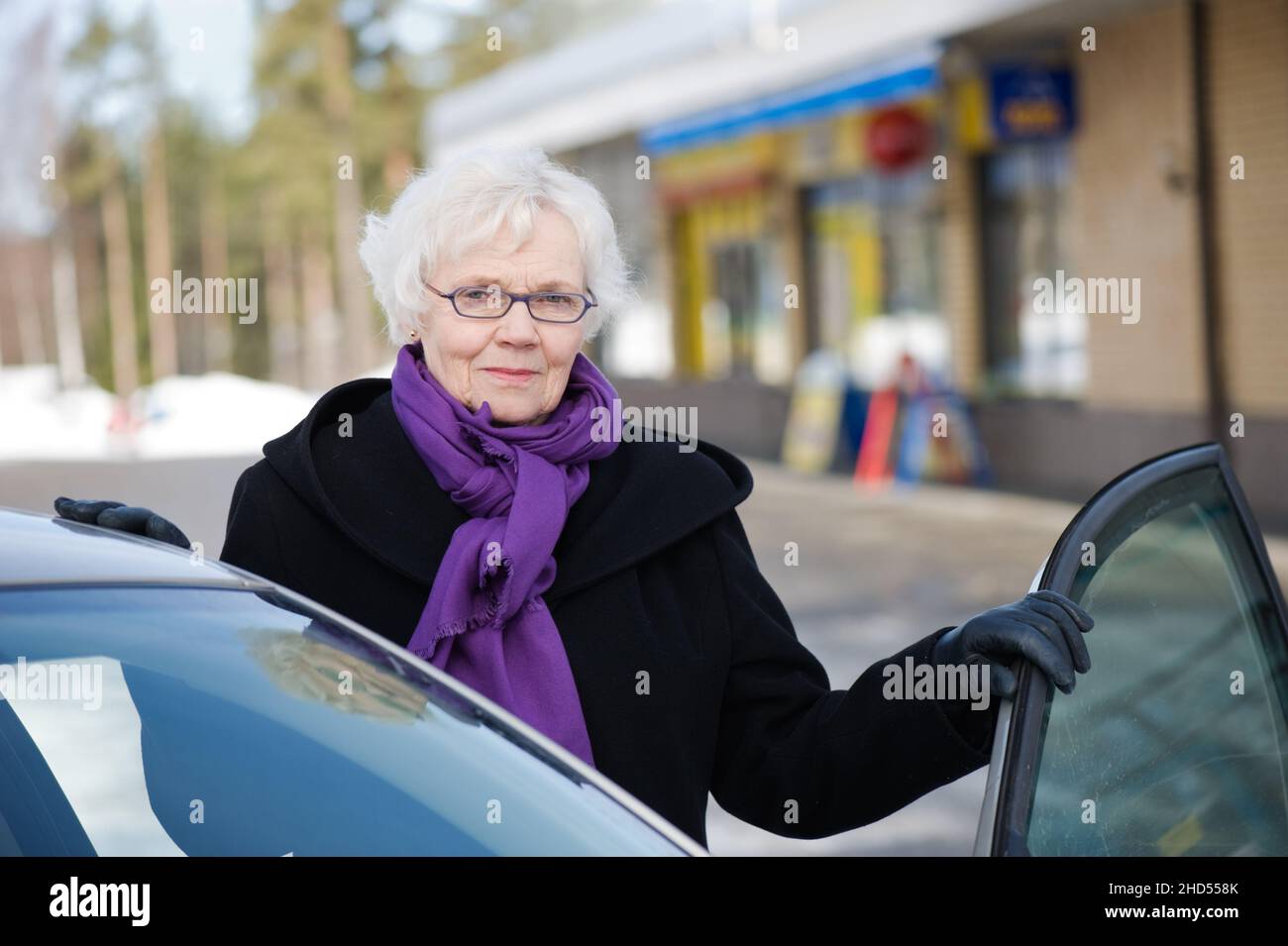 Donna anziana di stile in piedi accanto alla sua auto. Foto Stock