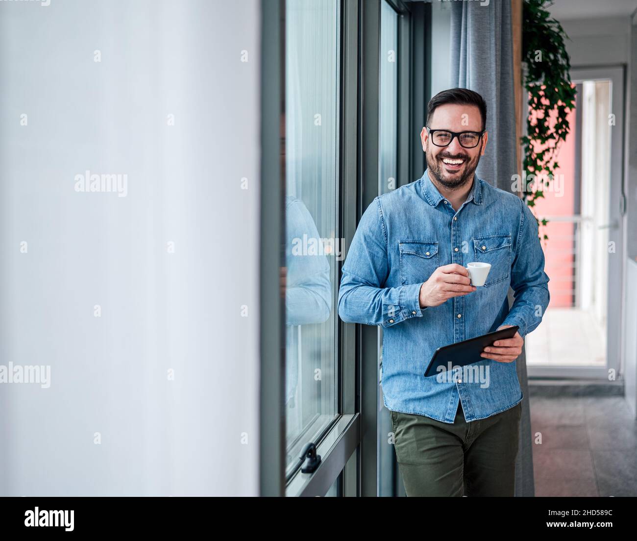 Ritratto di giovane adulto sorridente uomo d'affari allegro in ufficio domestico bere caffè mattina routine di partenza giorno felice bell'imprenditore riuscito Foto Stock