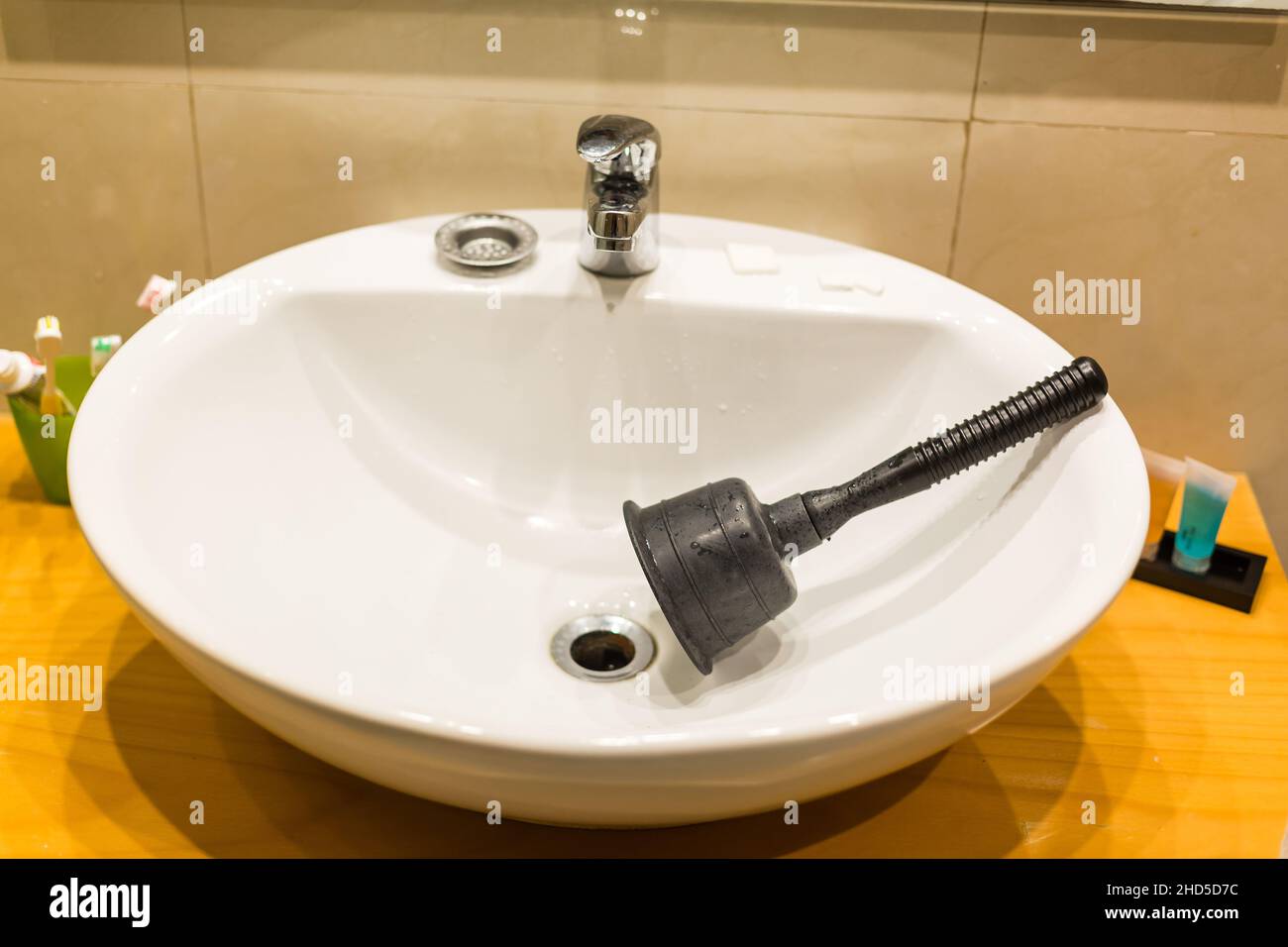 Utensile a stantuffo lavello nero per uso domestico nel lavandino della stanza da bagno tappato con disfag in materiale rosa, utensile di drenaggio appiattito con tazza in gomma e albero in legno o. Foto Stock