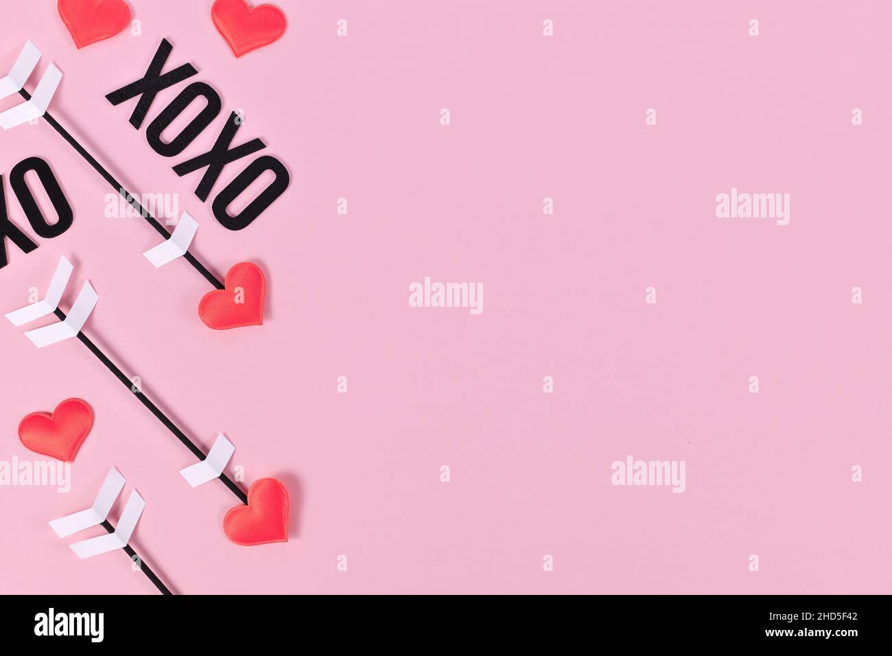 San Valentino piatto posato con le frecce amore Cupido e testo XOXO su sfondo rosa con spazio copia Foto Stock
