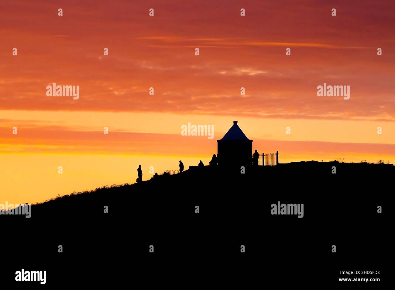 Il piccolo edificio panoramico sulla cima di Towan Head, caratterizzato da un intenso e spettacolare tramonto dorato a Newquay, in Cornovaglia. Foto Stock
