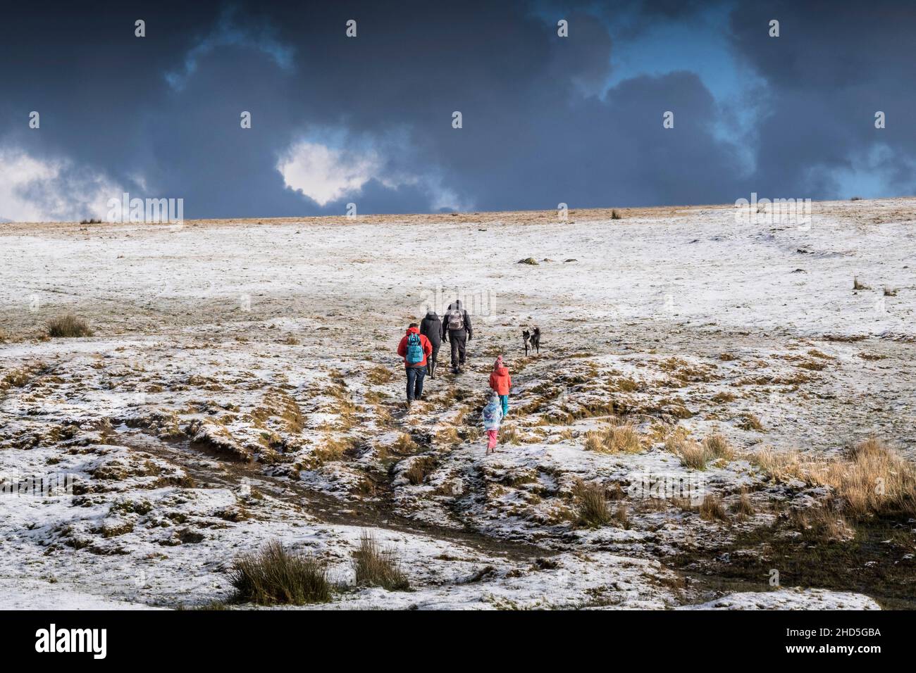 Una famiglia che cammina attraverso la neve sul selvaggio Rough Tor a Bodmin Moor in Cornovaglia. Foto Stock