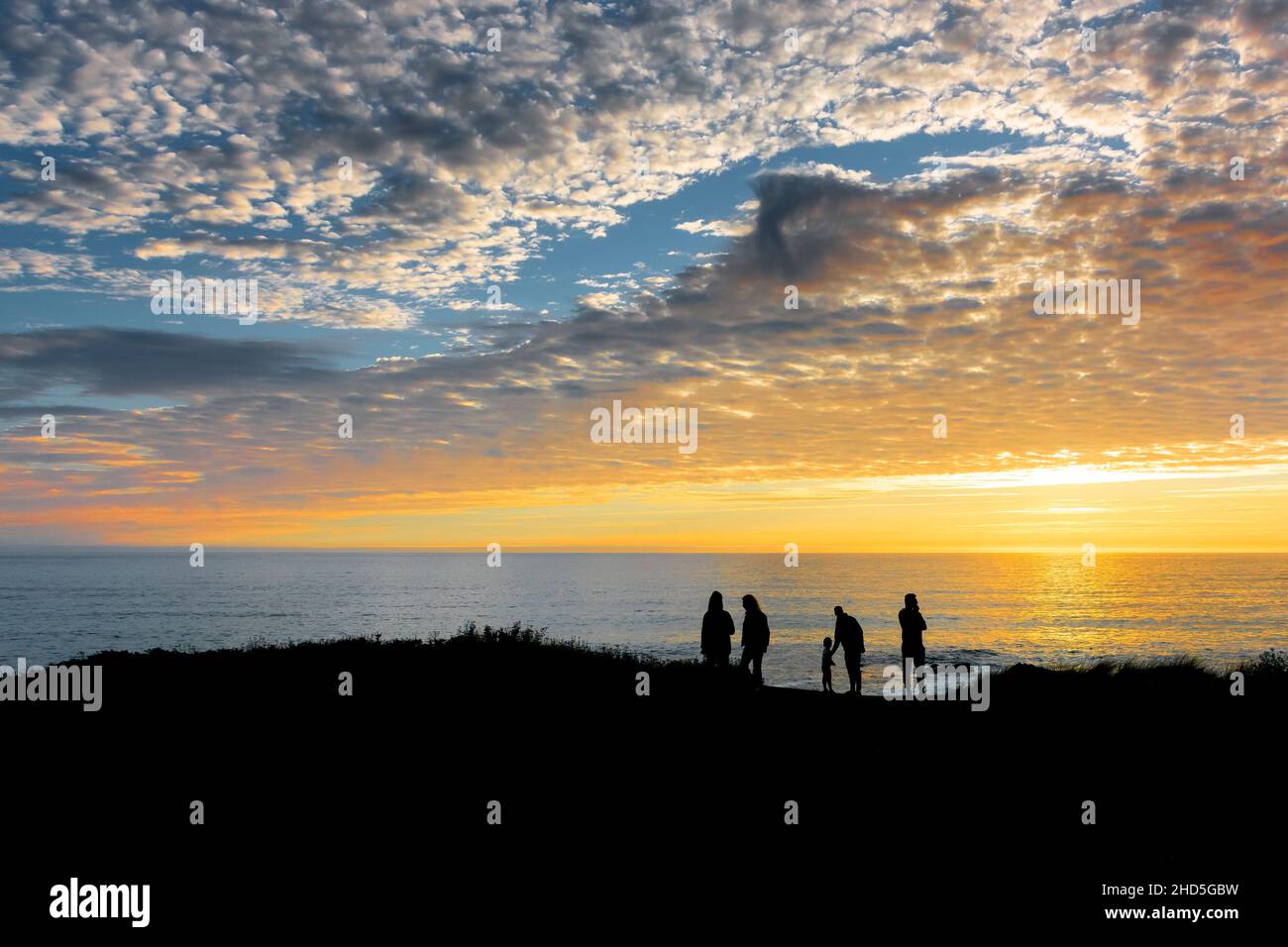 I turisti che si erono sulla costa silhouette da uno splendido e colorato tramonto su Little Fistral sulla costa di Newquay in Cornovaglia. Foto Stock