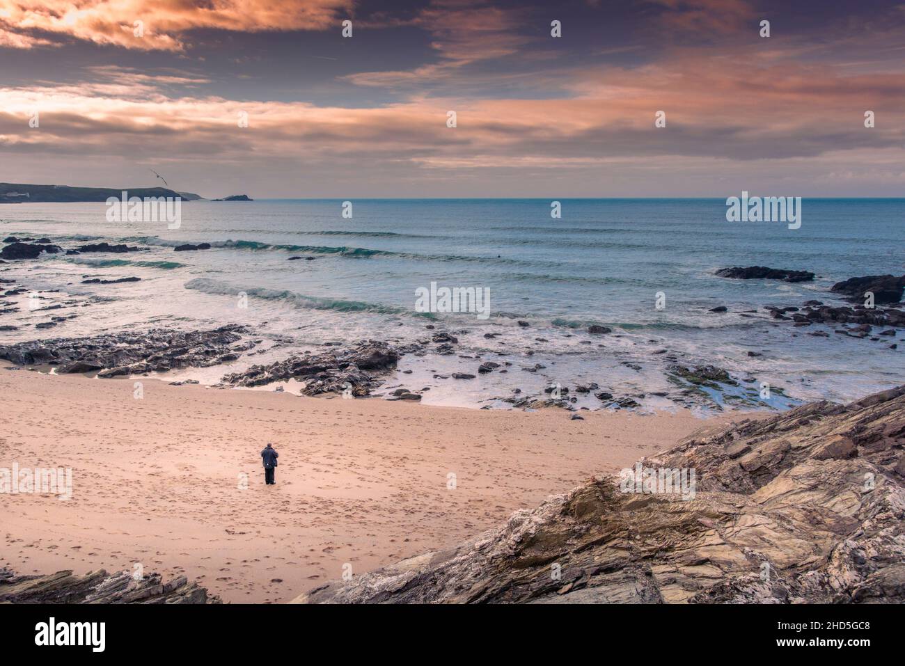 Un uomo in piedi da solo sulla spiaggia a Little Fistral a Newquay in Cornovaglia. Foto Stock