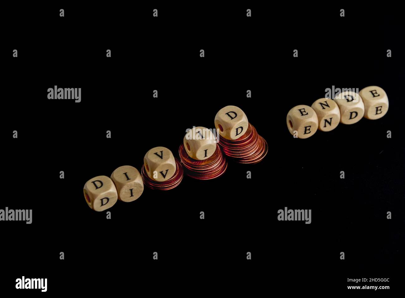 Punti metallici di monete con lettere a cubetti di legno che formano la parola 'Divid Ende' in lingua tedesca, immagine concettuale per la fine del dividendo. Foto Stock