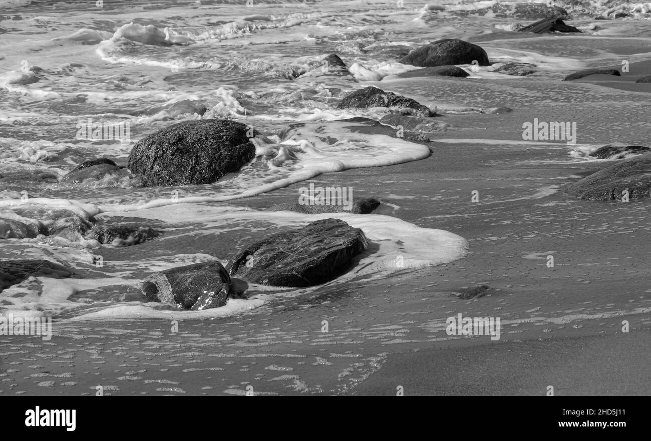 l'acqua dell'oceano che scorre oltre le rocce mentre torna in mare a spiaggia sabbiosa punto, Foto Stock