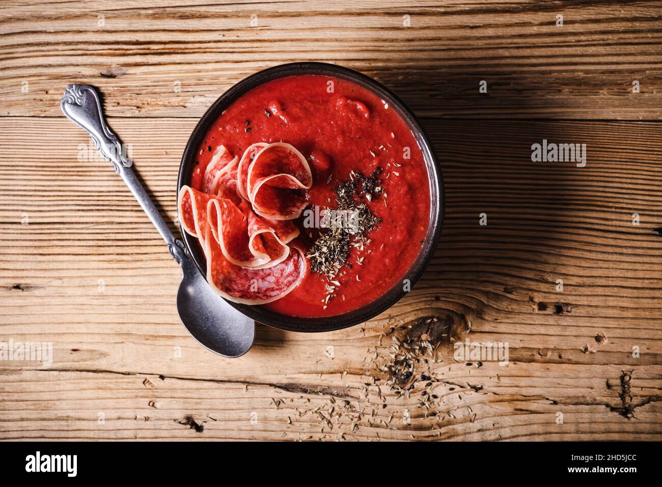 Ciotola di zuppa di pomodoro con carne deli su tavola rustica di legno direttamente sopra Foto Stock