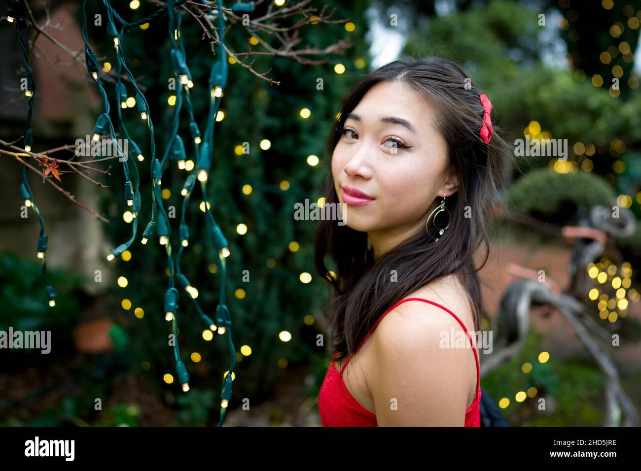 Primo piano di giovani asiatici orientali in piedi con luci di Natale Foto Stock