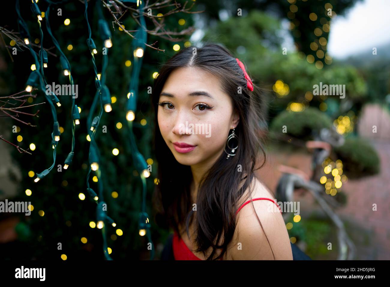 Primo piano di giovani asiatici orientali in piedi con luci di Natale Foto Stock