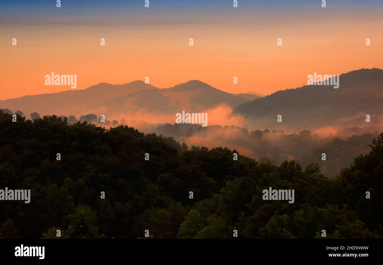 Il sole si adagia sulle Smoky Mountains nel North Carolina e la nebbia che si assestano nella valle Foto Stock