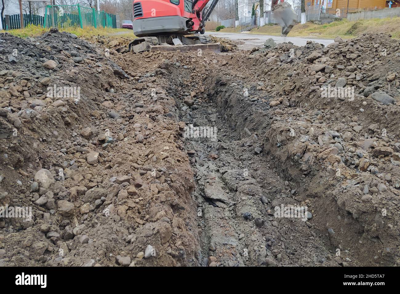 Un escavatore scava una trincea per liquame e acqua piovana lungo la strada, un escavatore cingolato. Foto Stock