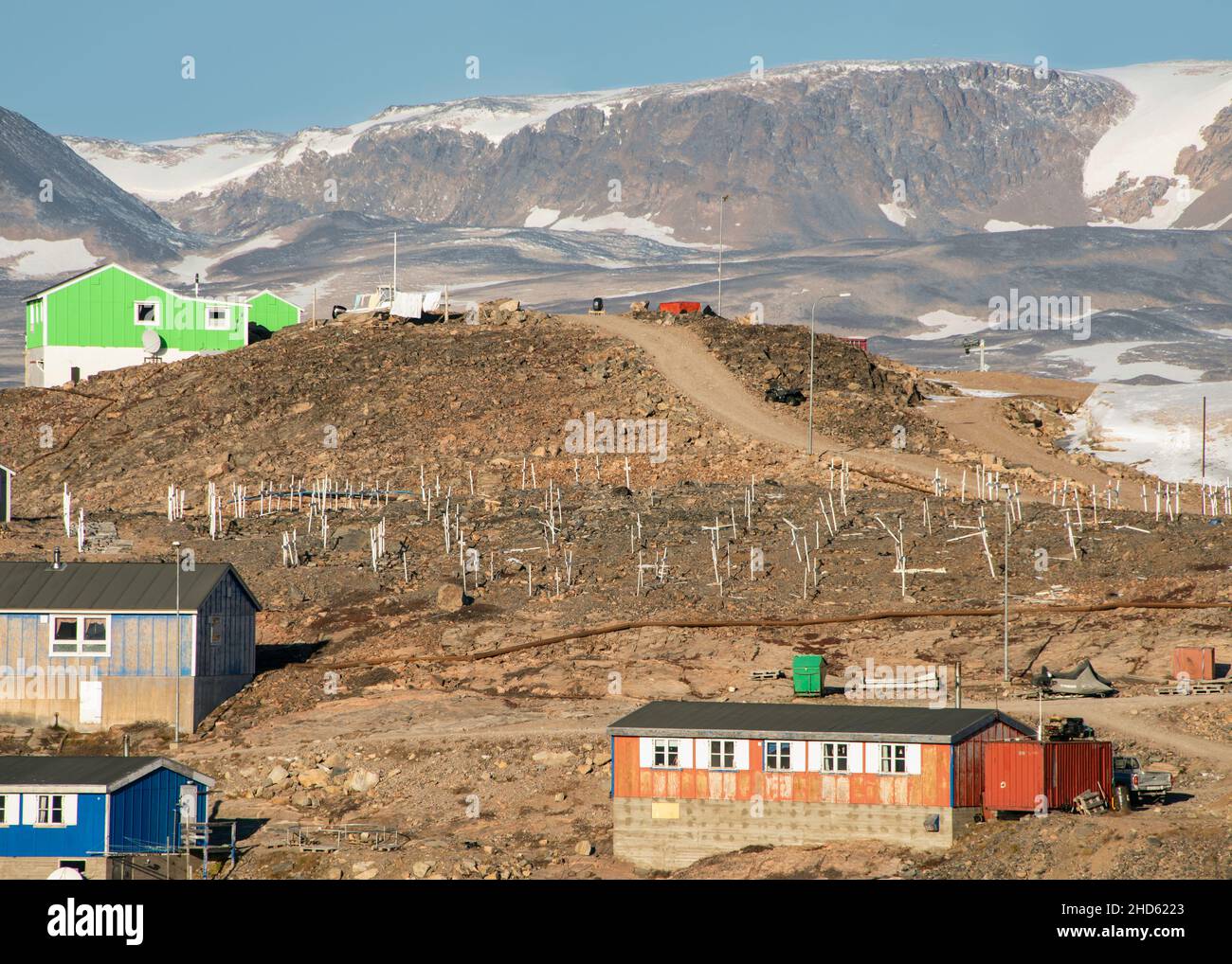 Vecchio cimitero con macchie di neve e montagne a Ittoqortoormiit, Lincoln Land, Scoresby Sund, Groenlandia Foto Stock