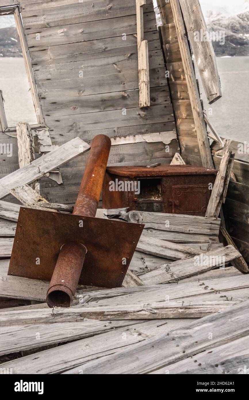 Stufa in metallo arrugginito e tubo di stufa all'interno di una vecchia cabina in rovina sulle rive di Danmark o , Fonjord, Scorseby Sund, Groenlandia Foto Stock