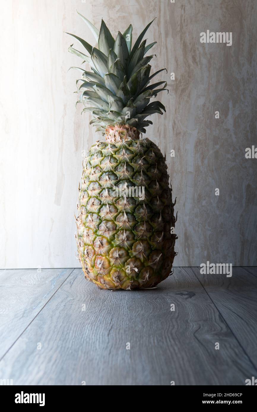 ananas e arance in primo piano su legno su sfondo marmoreo. Hald in ombra Foto Stock