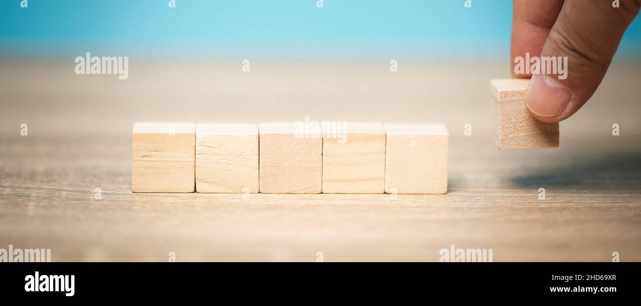 Mano dell'uomo che tiene un blocco di legno posato sul tavolo, idee di vendita, concetto di affari, crescita economica. Foto Stock