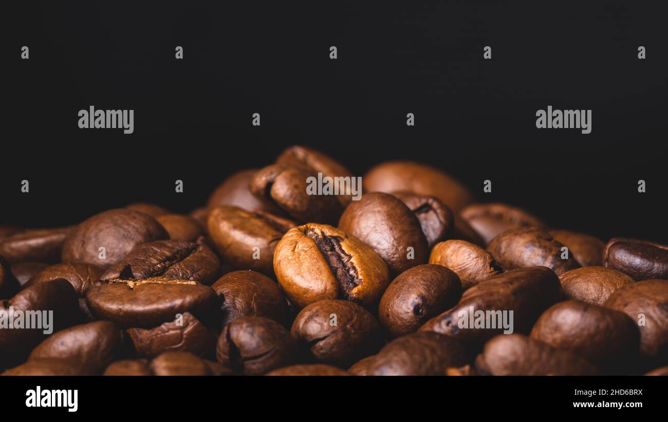 Chicchi di caffè arrosto fondo telaio pieno primo piano macro marrone scuro Foto Stock